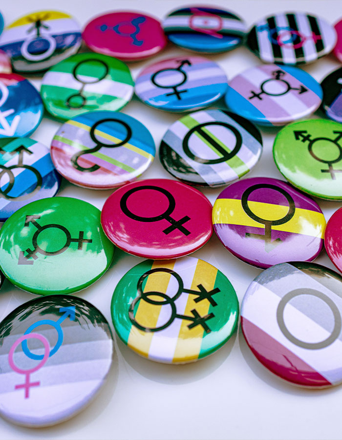 Colorful pins displaying various gender and sexuality symbols representing greys*xuality and modern dating culture trends.