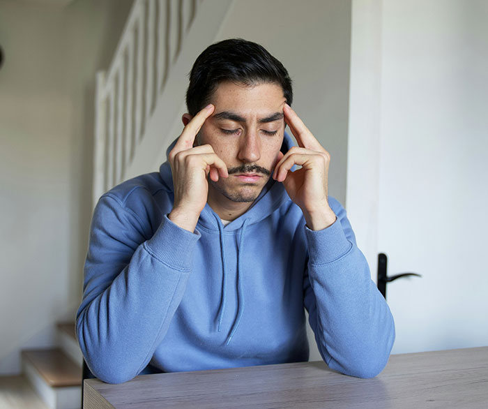 Young man in a blue hoodie sitting alone, deep in thought, reflecting on a friends call two decades later. Young man in a blue hoodie sitting alone, deep in thought, reflecting on a friends call two decades later.