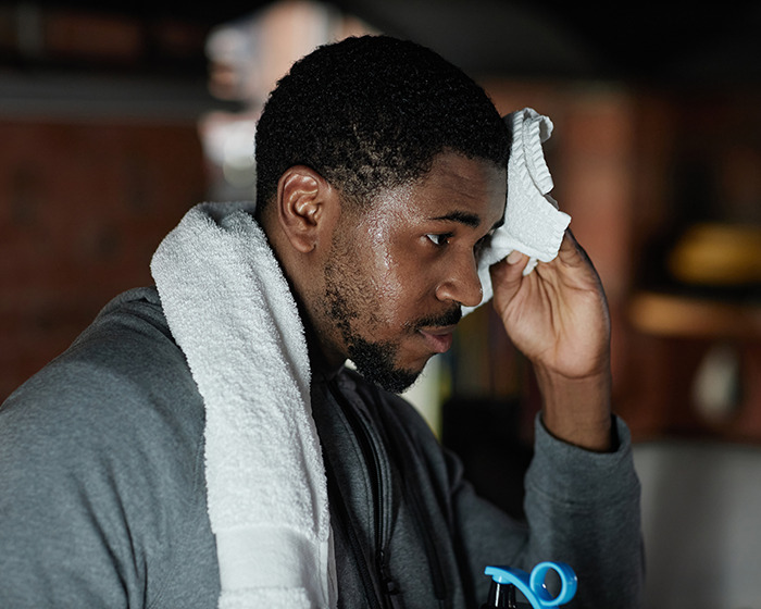 Gymgoer wiping sweat with towel after workout, highlighting common post-workout mistake and expert prevention tips.