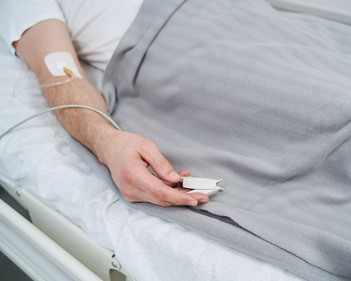 Close-up of a gymgoer lying in hospital bed with IV drip, highlighting a common post-workout mistake and recovery.