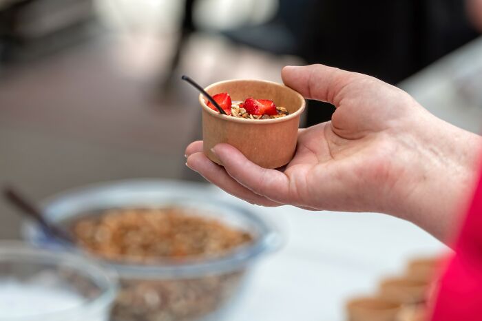 Hand holding a small bowl of healthy granola with strawberries, illustrating tips on how to lose weight effectively.