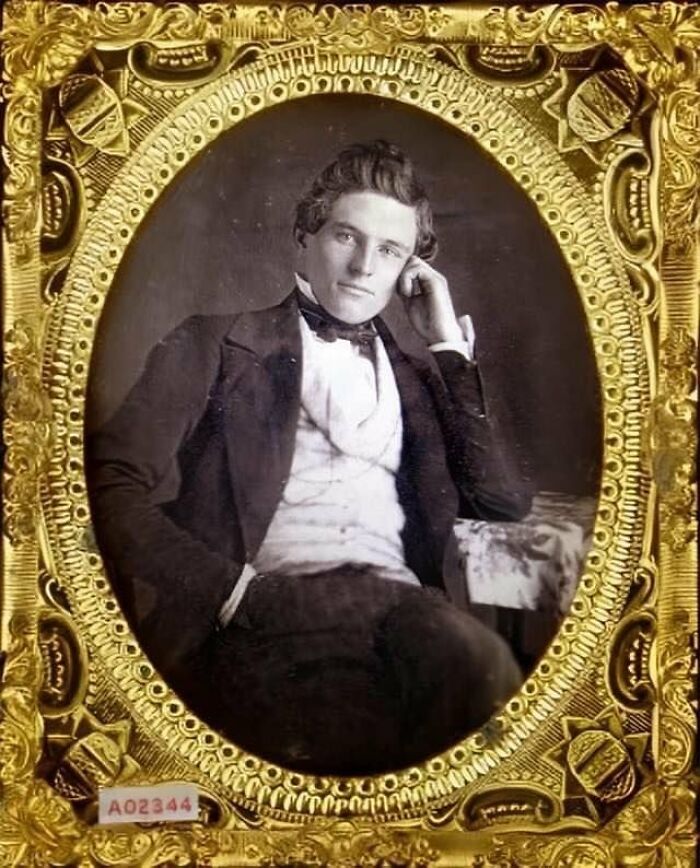 Victorian man in formal attire seated and posing thoughtfully, framed in an ornate vintage gold frame.