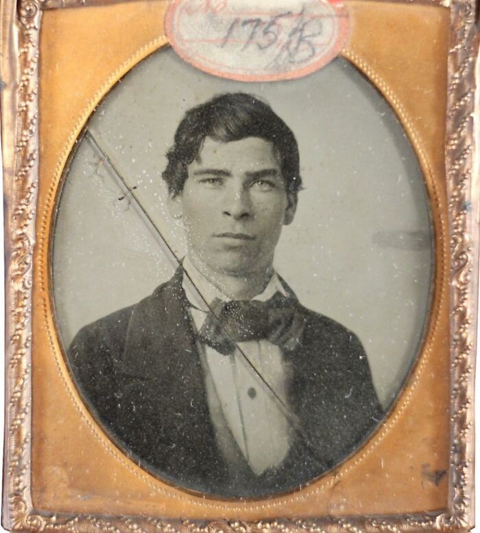 Victorian man in formal attire with bow tie, captured in a vintage framed portrait from the 19th century.