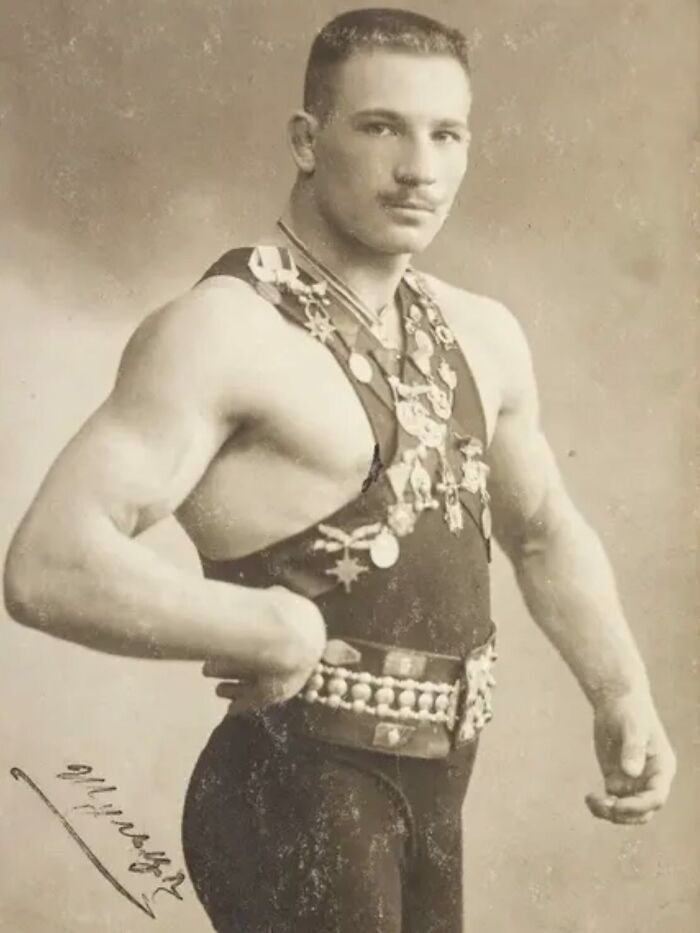 Victorian man with muscular build wearing a medal-adorned outfit, showcasing strength and Victorian era charm.