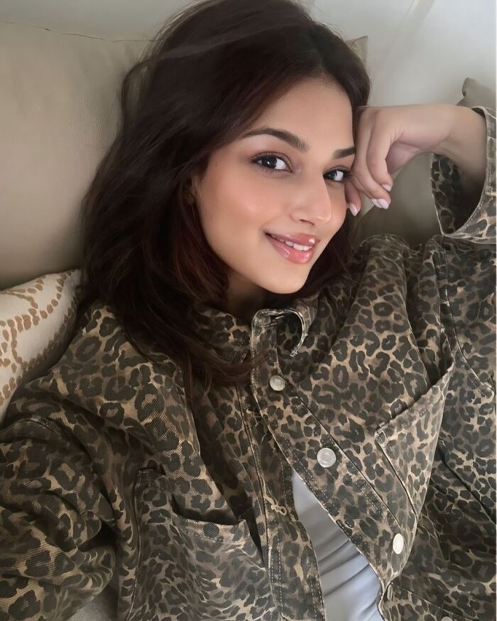 Woman smiling and relaxing indoors wearing a leopard print jacket, representing Miss Universe winners in stunning photos.
