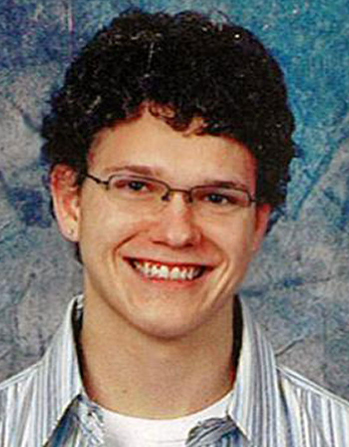 Young man with glasses smiling in a portrait photo related to chilling messages before going missing cases.
