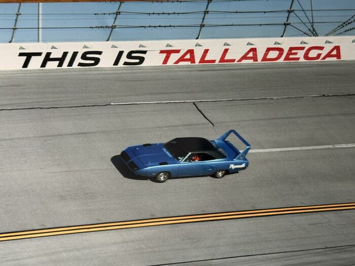 Blue Plymouth muscle car racing on Talladega track, featured in a popular online thread of exciting car pics.