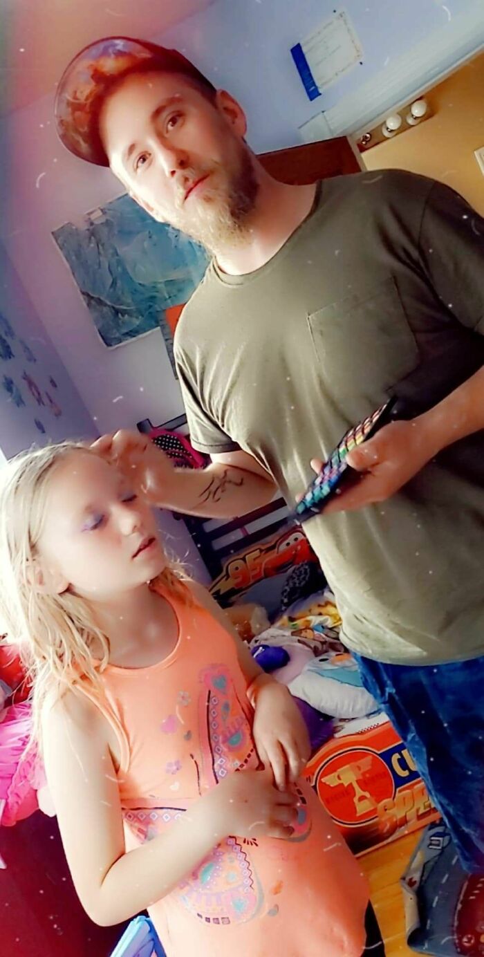 Man applying makeup to young girl indoors, capturing a moment that any man would be excited to see in a photo.