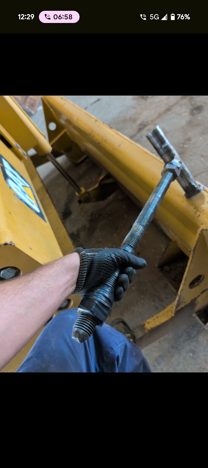 Man wearing work glove holding a large threaded bolt, showcasing a unique tool in a workshop setting any man would be excited to see