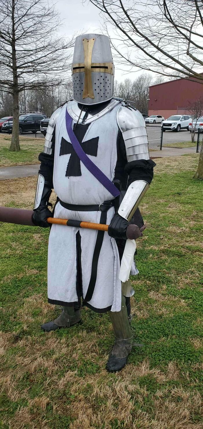 Man dressed in medieval knight armor holding a padded weapon outdoors, an image any man would be excited to see.