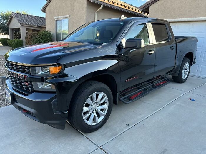 Black Chevrolet pickup truck parked in a driveway of a suburban house, showcasing a rugged design men would appreciate.