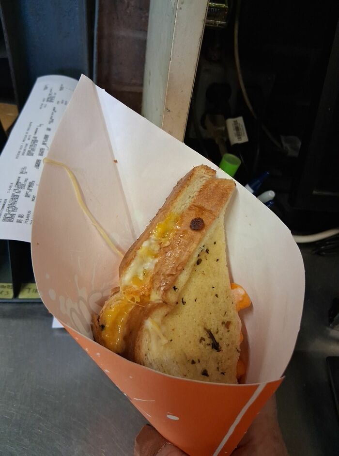 Grilled cheese sandwich with melted cheese served in a paper cone, a food item any man would be excited to see.