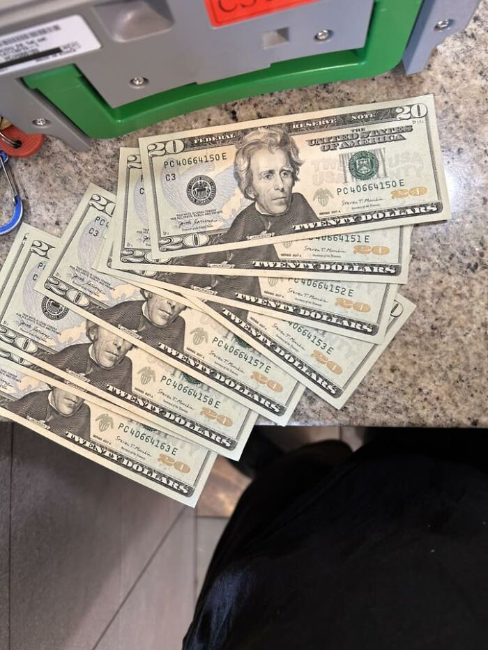 A stack of twenty-dollar bills fanned out on a countertop near an ATM, showing cash excitement for men.