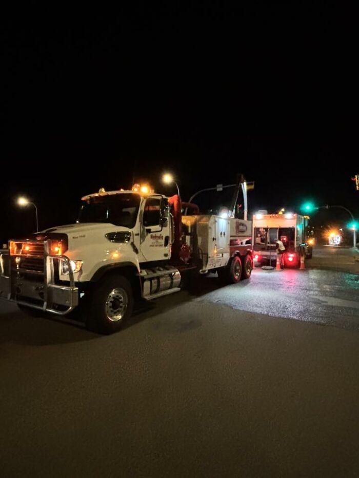 Tow trucks lined up with flashing lights at night on a street, a scene any man would be excited to see