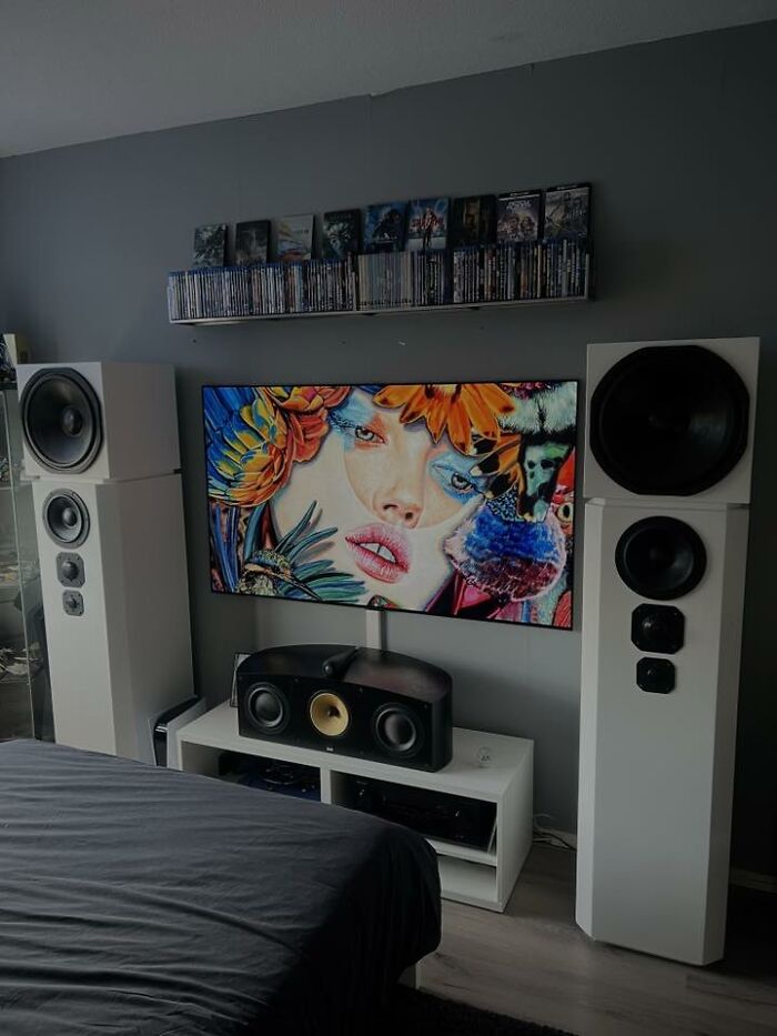 Modern home entertainment setup with large speakers, vibrant digital art on TV, and shelves of movies, any man would be excited to see.