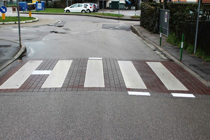 Pedestrian crosswalk with artistic brick and concrete pattern blending street art and urban design elements.