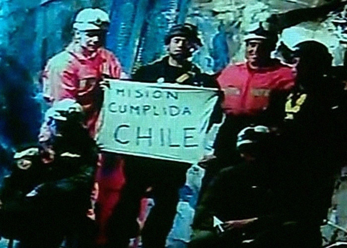 Miners in helmets holding a sign inside a cave, representing unbelievable historical survival events in Chile.