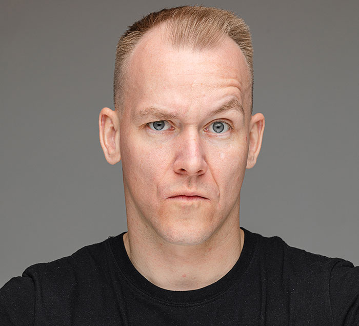 Man with raised eyebrow and skeptical expression showcasing surprising body quirks in a neutral background.