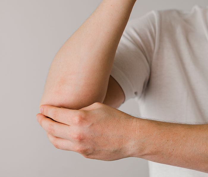 Close-up of a person holding their elbow, illustrating surprising body quirks that may change how you see yourself.
