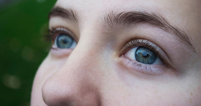 Close-up of a person’s blue eyes and natural skin texture highlighting surprising body quirks and unique features.