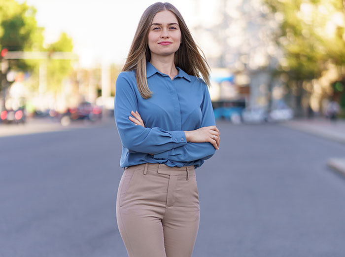 Young woman standing confidently on a city street showcasing surprising body quirks with a calm expression.