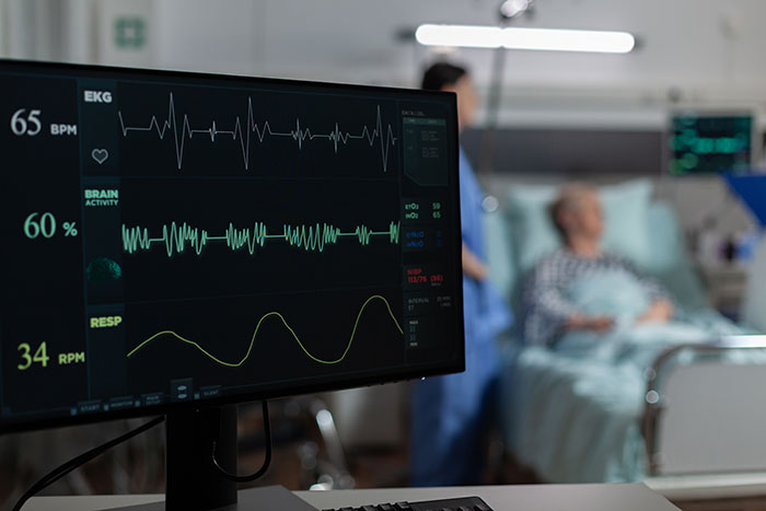 Hospital heart monitor displaying vital signs with patient and nurse in the background illustrating surprising body quirks.