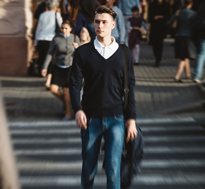 Young man walking on a busy city street, showing unique body quirks that highlight surprising human traits in daily life.