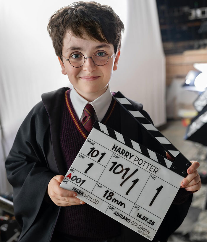 Child dressed as Harry Potter holding a film clapperboard on set, related to Harry Potter books controversy.