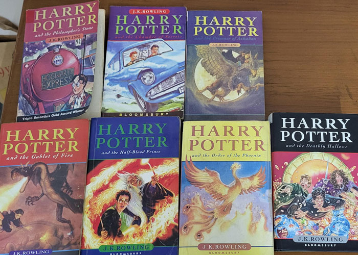 Set of Harry Potter books laid out on a wooden surface, highlighting a family conflict over giving kids Harry Potter books.