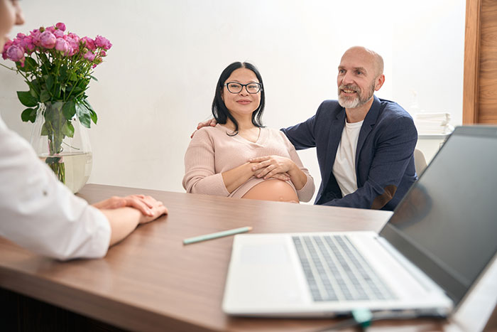 Pregnant woman with partner at medical consultation, mom of 6 boys curious if sister is expecting a girl, getting cut off. - 10
