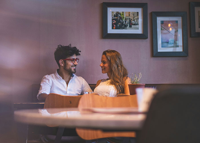 Couple smiling and talking in a cozy caf&eacute;, symbolizing a woman&rsquo;s life turned upside down after husband&rsquo;s confession of love.