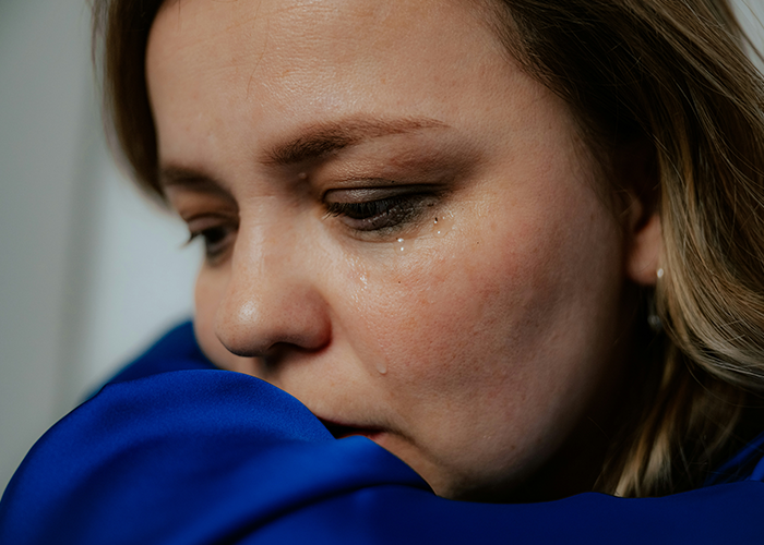 Close-up of a woman in emotional distress, tears falling, reflecting a life turned upside down after husband's confession.