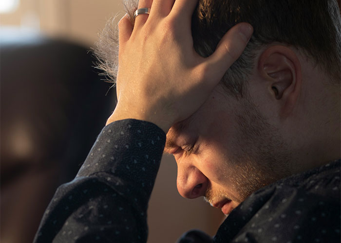 Man holding head in distress, reflecting on difficult confession about love involving colleague and woman&rsquo;s life challenges.