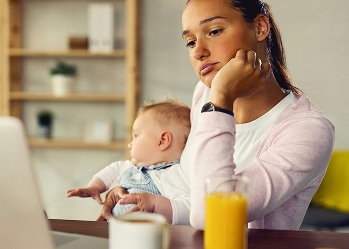 Woman looking pensive and holding baby at home, reflecting on life turned upside down after husband's confession of love for colleague