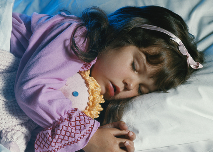 Young girl sleeping peacefully in bed holding a doll, symbolizing a woman's life turned upside down by love confession.