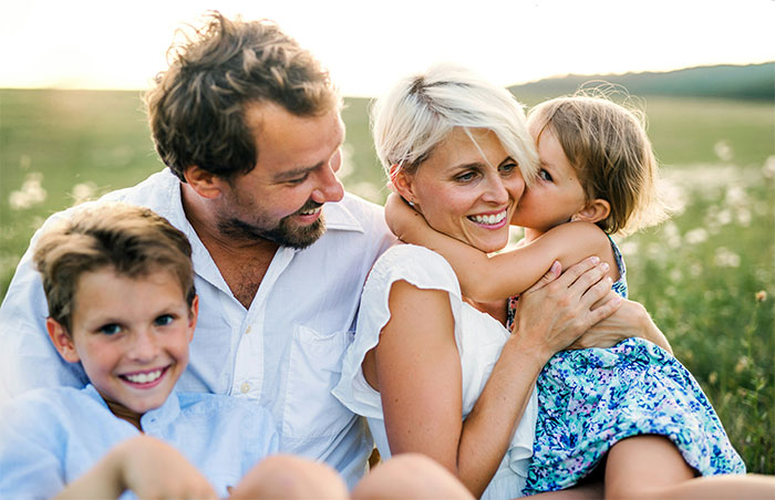 Happy family outdoors with husband, wife, and children sharing a moment after marriage therapy discussions. - 45