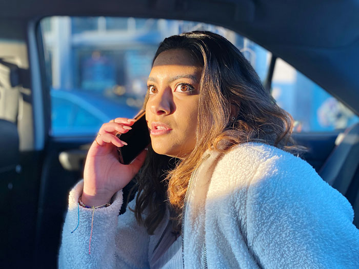 Woman in a white jacket on phone, upset after hubby mocks wife over mispronunciation while she shares surgery details