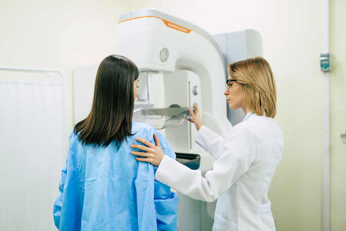 Woman in medical gown receiving diagnostic imaging while healthcare professional explains surgery details during appointment