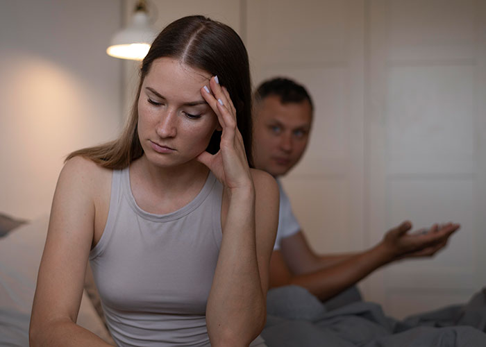 Woman looking distressed while her husband gestures in the background, showing relationship tension after their wedding.