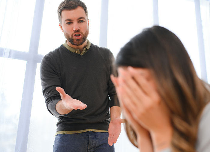 Man demanding divorce from wife, arguing in a bright room while wife covers her face in distress. Man demanding divorce from wife, arguing in a bright room while wife covers her face in distress.