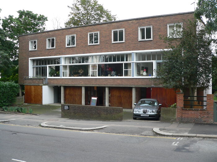 Modern iconic architectural homes with large windows and wooden garage doors in a suburban neighborhood street view.