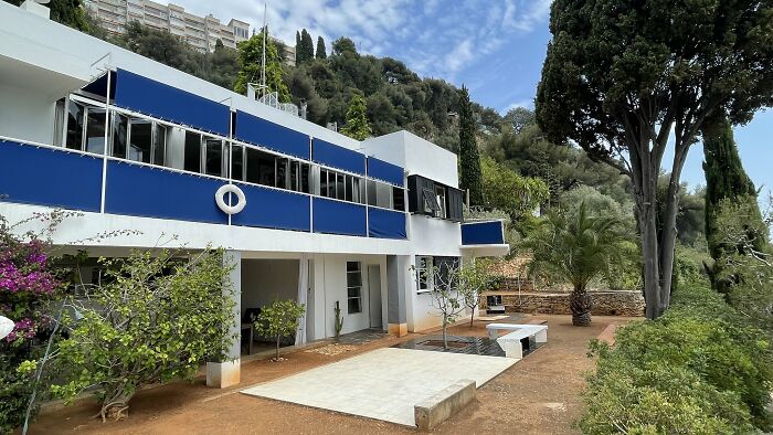 Modern iconic architectural homes with clean lines, large blue balconies, and surrounding greenery in a hillside setting.