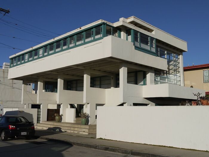Modern iconic architectural homes featuring elevated design with large windows and clean geometric lines on a sunny day.