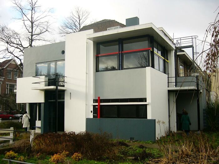 Modern iconic architectural homes with geometric shapes and clean white facade surrounded by bare trees in winter.