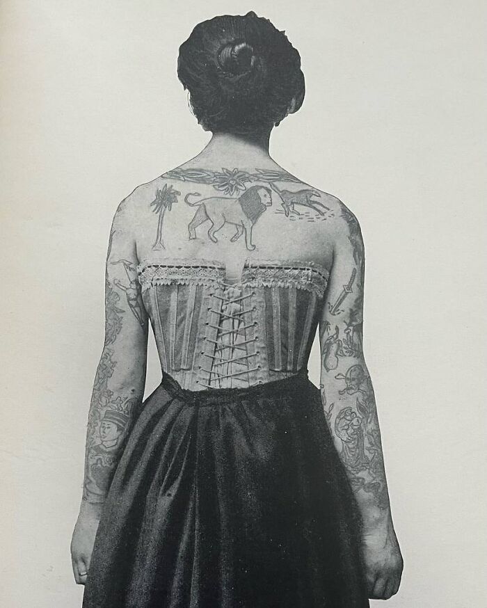Black and white photo of a tattooed woman from the past wearing a corset, showcasing weird history pics and vintage tattoos.