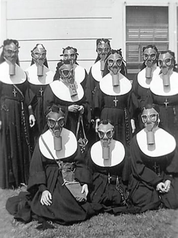 Group of nuns wearing early 20th-century gas masks posing outside, a weird history pic showing unusual past safety measures.