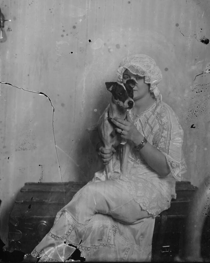 Black and white vintage photo of a woman in lace dress holding a dog, showcasing weird history moments from the past.