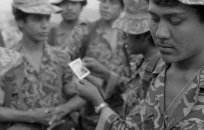 Group of soldiers in camouflage uniforms examining a photograph, a weird history picture capturing a unique past moment