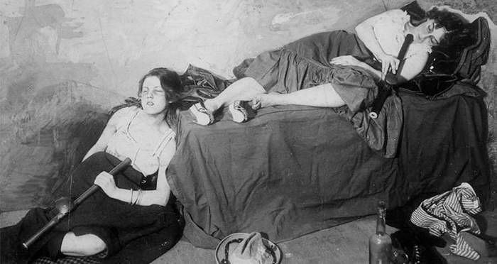 Two women in old-fashioned clothes holding rifles in a dim room, a weird history picture showing unusual past moments.