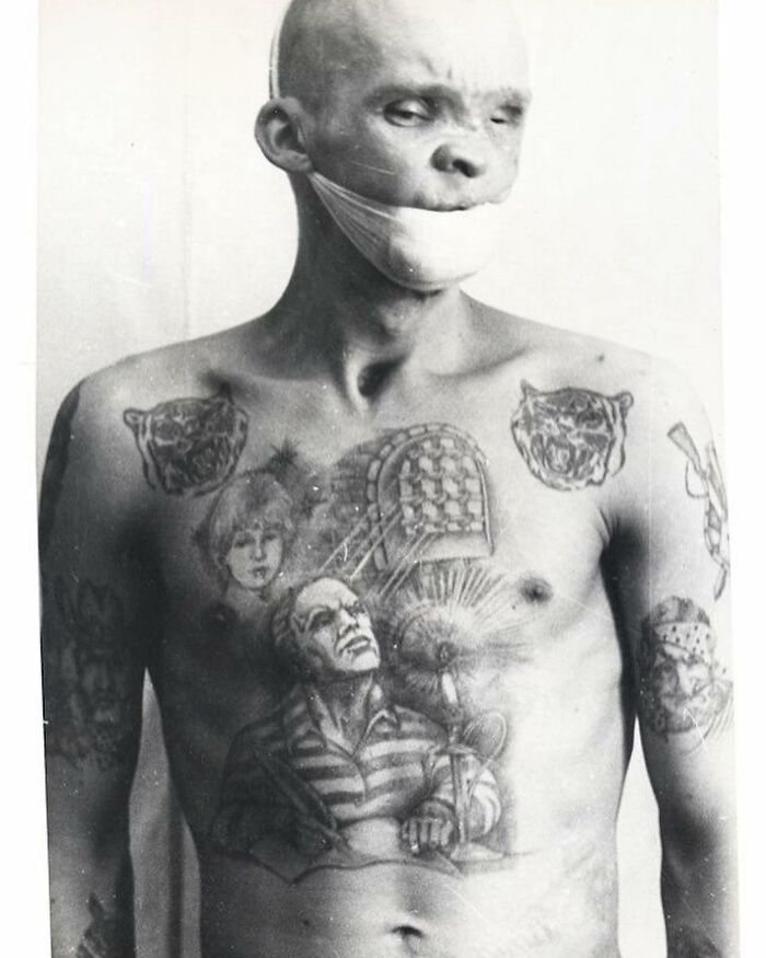 Black and white photo of a tattooed man with a bandage covering his mouth, showing weird history pics from the past.